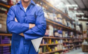 Mid section of supervisor standing with arms crossed in warehouse